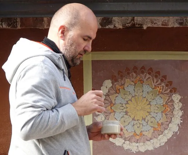 Anvar Valge making mandala stencil design with clay plasters / Photo: © Eestimaaehitus